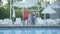 Portrait happy mature couple standing at the swimming pool hugging their little granddaughter. Grandmother and