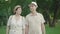 Portrait of happy mid-adult husband and wife walking together in summer park and talking. Cheerful man and woman