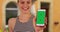 Portrait of happy millennial girl holding smartphone with green screen display
