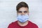 Portrait of happy millennial man smiling in front of camera while wearing medical protective mask for coronavirus spread