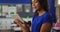 Portrait of happy mixed race female teacher standing in classroom with tablet children in background