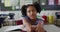 Portrait of happy mixed race schoolgirl sitting at classroom, answering question, looking at camera