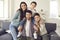 Portrait of happy mother, father and little children sitting on couch and smiling at camera