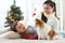 Portrait of a happy mother and her little son with dog spending together Christmas time at home near the x-mas tree