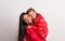 Portrait of a happy mother holding a small girl with red anorak in studio.