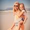 Portrait of happy mother piggybacking her daughter at beach