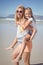 Portrait of happy mother piggybacking her daughter at beach