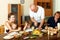 Portrait of happy multigeneration family eating chicken with wi