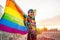 Portrait of happy non-binary person waving rainbow flag