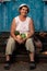 Portrait of happy old woman pensioner sitting on doorstep of her house with crop of vegetables in her hands