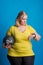 Portrait of a happy overweight woman with smartwatch and heavy ball in studio.