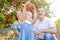 Portrait of happy parents with cute little blondy baby girl daughter picking ripe pomegrate fruit in the garden. Harvest and famil