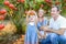 Portrait of happy parents with cute little blondy baby girl daughter picking ripe pomegrate fruit in the garden. Harvest and famil