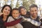 Portrait of happy parents piggybacking kids outdoors