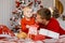 Portrait of a happy playful father and son opening a Christmas gift near beautiful New Year tree and looking cheerfully at camera