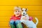 Portrait of happy preteen boy sitting on the ground playing with his yawning dog Jack Russell Terrier on yellow background outdoor