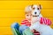 Portrait of happy preteen boy sitting on the ground playing with his yawning dog Jack Russell Terrier on yellow background outdoor