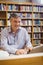 Portrait of happy professor sitting at desk using laptop