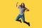 Portrait of happy rejoicing bearded young man with long curly hair in casual grey tshirt jumping and celebrating his vivtory with
