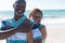 Portrait of happy retired african american senior couple standing together at beach on sunny day