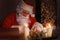 Portrait of happy Santa Claus sitting at his room at home near Christmas tree and answering Christmas letters