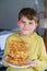 Portrait of happy school kid boy holding fresh baked waffles. Smiling hungry child with sweet biscuit wafer. Sweet sugar