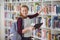 Portrait of happy schoolgirl selecting book in library