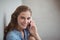 Portrait of happy schoolgirl talking on mobile phone in corridor