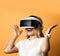 Portrait of happy screaming blonde woman in white t-shirt using VR glasses exploring augmented reality holding hands up