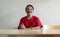 Portrait of happy senior Asian man sitting at wooden table with arm cross and looking at camera