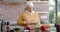 Portrait of happy senior caucasian woman cooking dinner in kitchen at home, slow motion