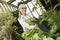 Portrait of a happy senior gardener cultivating plants in greenhouse