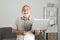 Portrait of happy senior office worker with a laptop. Senior man with a gray beard has a job in laptop at home office