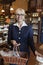 Portrait of a happy senior owner standing with basket full of spices in store