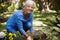 Portrait of happy senior woman kneeling while planting flowers