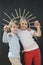 Portrait of happy siblings holding chalks against blackboard