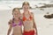 Portrait Of Happy Sisters Standing On Beach