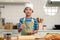 Portrait of happy smiling Asian boy wearing apron and chef hat, stirring and mixing eggs in glass bowl, cute child cooking meal at