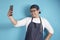 Portrait of happy smiling Asian chef or waiter doing selfie self portrait photograph on his phone