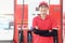 Portrait of happy smiling Asian gas station attendant in red uniform standing with crossed arms at gas station