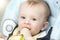 Portrait of happy smiling baby eating in highchair at kitchen