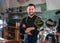 Portrait of happy smiling bearded barman dressed in a black uniform with an apron at bar counter with draught beer taps.