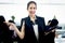 Portrait of happy smiling beautiful Asian woman officer holds tablet, standing at office with blurred background of busy working