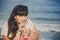 Portrait of happy smiling beautiful overweight young woman in white T-shirt drinking sweet coffee through straw outdoors at beach