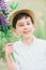 Portrait of happy smiling boy holding bouquet of lupines on green grass against sky. Soft focus. Summer activities