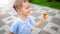 Portrait of happy smiling cheerful toddler boy running in park and holding small toy helicopter. Kids positive emotions