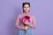 Portrait of happy smiling nice young dark haired girl in casual attire, holding bouquet of peony flowers, standing over lilac