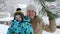 Portrait of happy smiling toddler boy with mother enjoying falling snow from tree branch at park