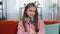 Portrait of happy smiling young girl child kid with headphones around neck sitting on home sofa