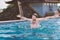 Portrait of happy smiling young man with hands up, which is bathed in pool on roof.